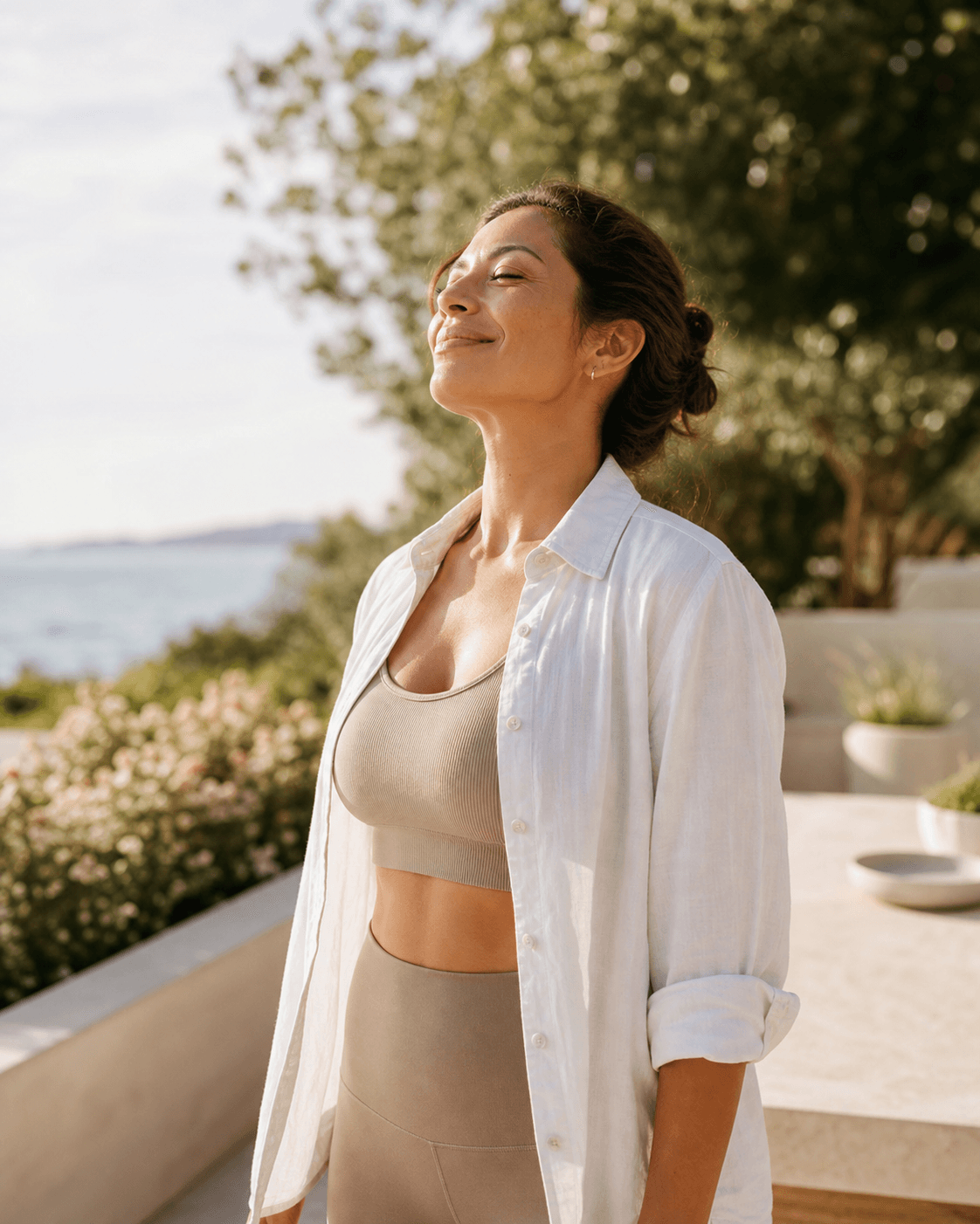 Woman enjoying sunlight on a coastal garden terrace after a wellness routine